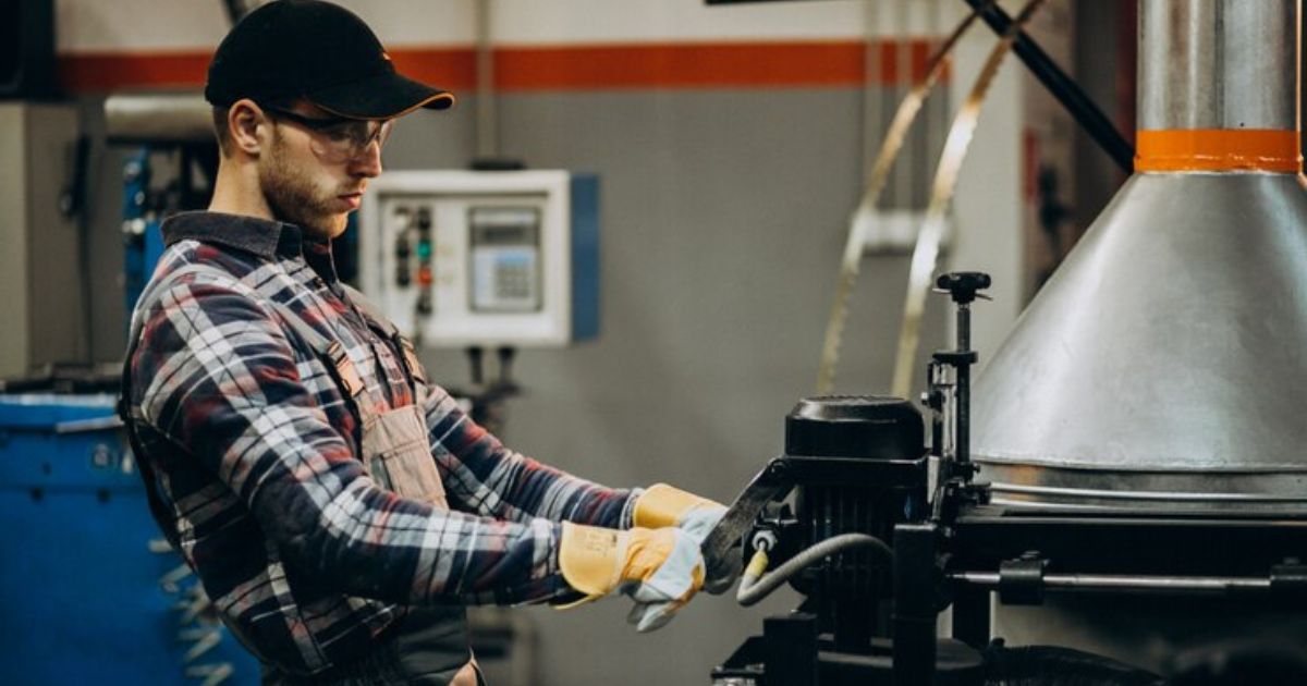 Worker operating a CNC press brake machine in an industrial setting.